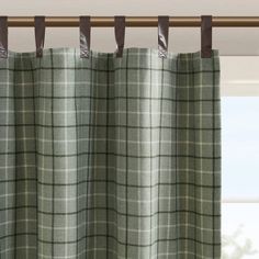 a window with green plaid curtains hanging from it's rod - end, in front of a window