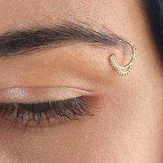 a close up of a person's eye with a gold nose ring on it