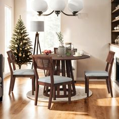 a dining room table with four chairs and a small christmas tree in the corner next to it