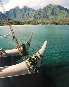 two sailboats in the water with mountains in the background