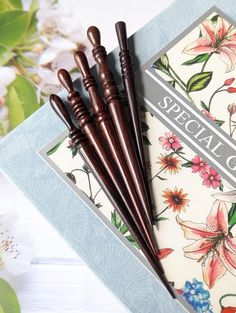 three wooden pens sitting next to each other on top of a card with floral designs