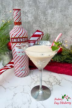 a drink in a martini glass next to a bottle with candy canes on it