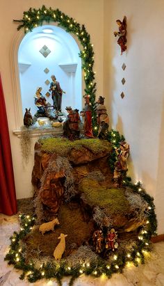 a nativity scene is displayed in the corner of a room with christmas lights and decorations