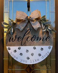 a welcome sign hanging on the front door of a dog's house with paw prints