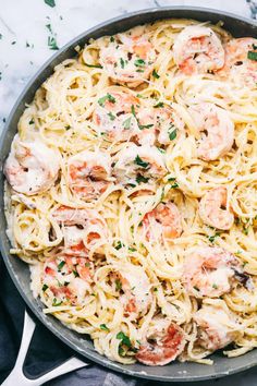 pasta with shrimp and parmesan cheese in a skillet on a marble surface