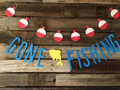 some fishing decorations are hanging on a wooden wall with the word gone fishing spelled in blue