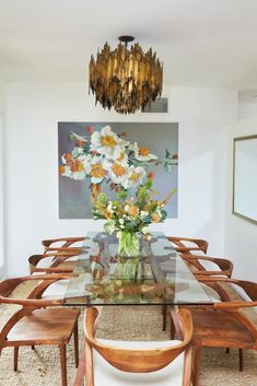 a dining room table with chairs and a vase filled with flowers on top of it