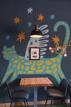 two chairs and a table in front of a wall with an animal painted on it