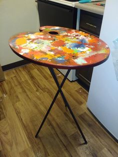 a table that has some paint on it and is in the middle of a kitchen