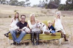 a family sitting on a couch with their dogs