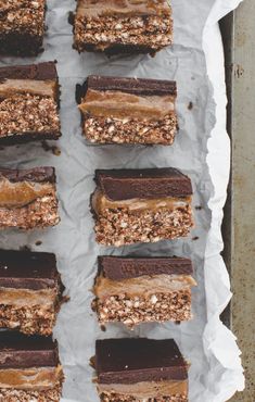 chocolate brownies with peanut butter frosting and pecans on top are lined up in a baking pan