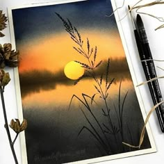 an image of the sun setting over water with some dry grass and leaves next to it