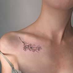 a woman's chest with a flower tattoo on the left side of her shoulder