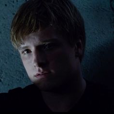 a young man is staring at the camera in this dark room with concrete walls and cement flooring