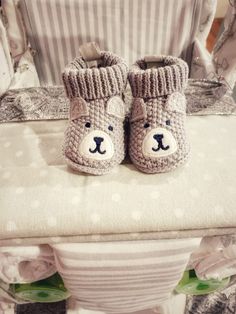 a pair of crocheted baby shoes sitting on top of a bed