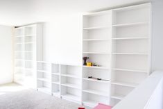 an empty room with white bookshelves and carpet