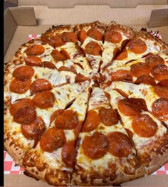 a pepperoni pizza in a box on a checkered tablecloth