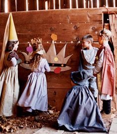 three children dressed up in costumes standing next to a wooden wall with paper cutouts on it