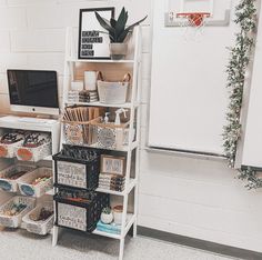 a white shelf filled with lots of baskets next to a wall mounted computer and basketball hoop