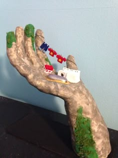 a hand that has some toy cars on it and trees in the middle of it