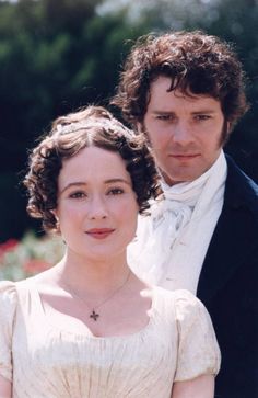 two people standing next to each other in formal clothes and one is wearing a white dress