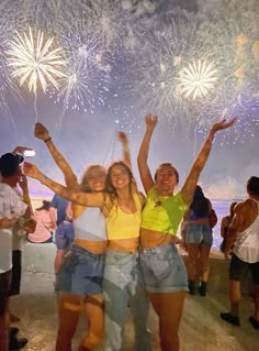 two women and a man are posing for a photo while fireworks go off in the background