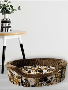 a dog bed sitting on top of a table next to a vase with flowers in it