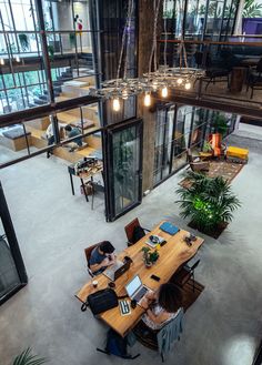 an overhead view of two people working on their laptops in the middle of a large room