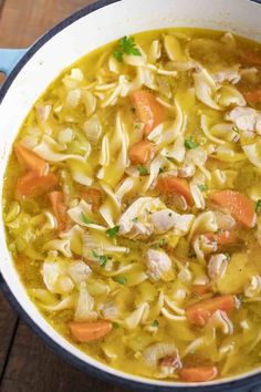 a bowl of chicken noodle soup on a wooden table