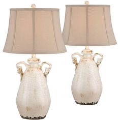 two white vases with lamps on top of each one, both have beige shades