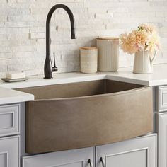 a kitchen sink sitting under a faucet on top of a counter next to a vase