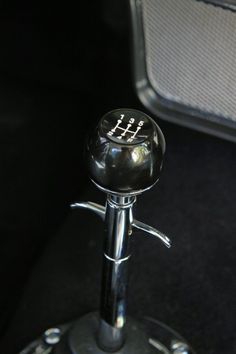 a close up of a metal object on a black surface with a speaker in the background