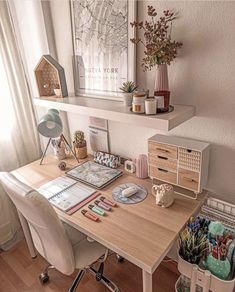 a desk with many items on it in front of a window and some bookshelves