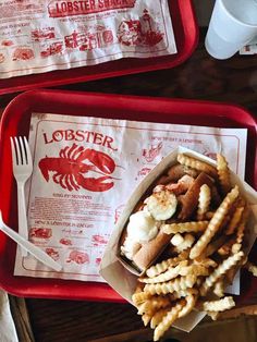 two trays filled with lobster and shrimp fries next to a cup of coffee on a table