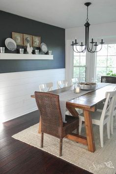 a dining room table with chairs and plates on the wall above it, in front of a window