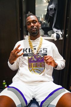 a man sitting in a locker room holding up a cell phone