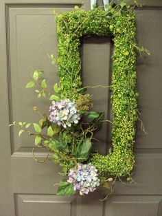 the letter d is decorated with flowers and greenery on it's front door