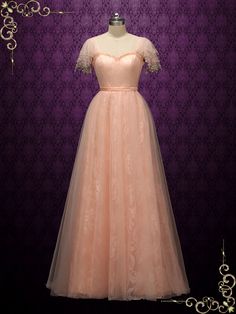 a pink dress on display in front of a purple wall with an ornate frame around it