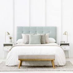 a bed with white sheets and pillows on top of it next to a night stand