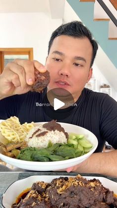 a man eating food from a white bowl on top of a table next to a stair case