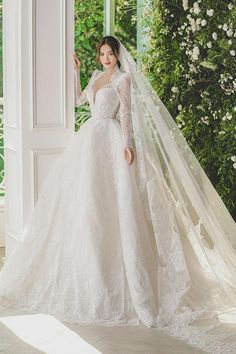 a woman in a white wedding gown and veil posing for the camera with her hand on her hip