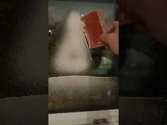 a person is cleaning the inside of a bathroom mirror with a red and white sprayer