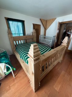 a large wooden bed sitting in a bedroom next to a baby crib on top of a hard wood floor