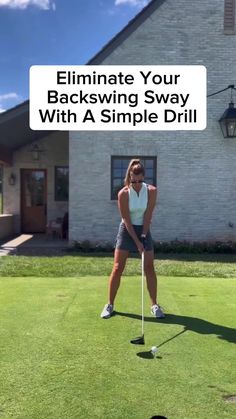 a woman hitting a golf ball with a tee on the grass in front of a house