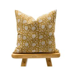 a yellow and white pillow sitting on top of a wooden chair