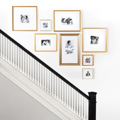 a stair case with pictures on the wall and framed photos above it, along with a banister