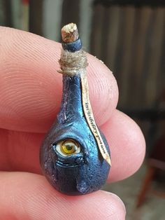 a tiny blue object with yellow eyes in someone's hand