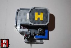 a lego clock with the letter h on it's face is shown in front of a white wall