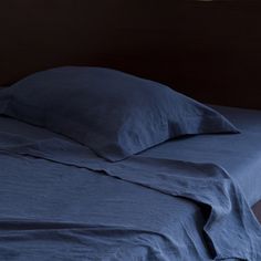 an unmade bed with blue sheets and pillows