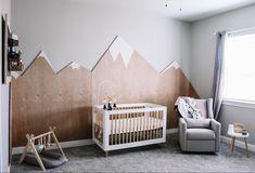 a baby's room with mountains painted on the wall and a rocking chair next to it